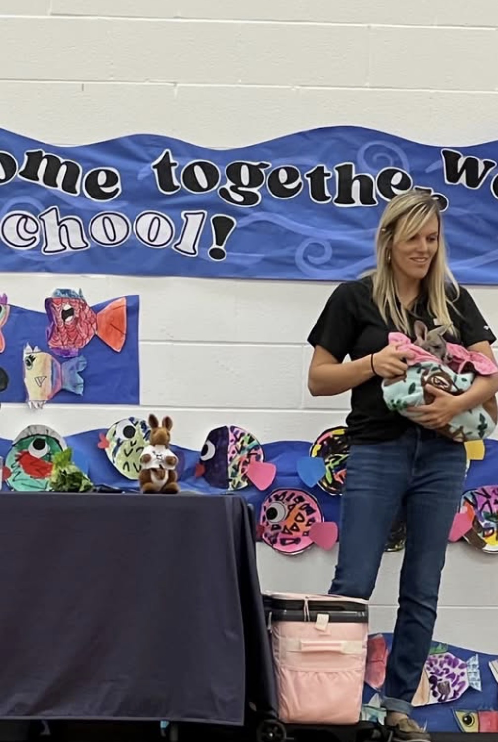 A Traveling Acres educator presenting a young kangaroo during a school assembly