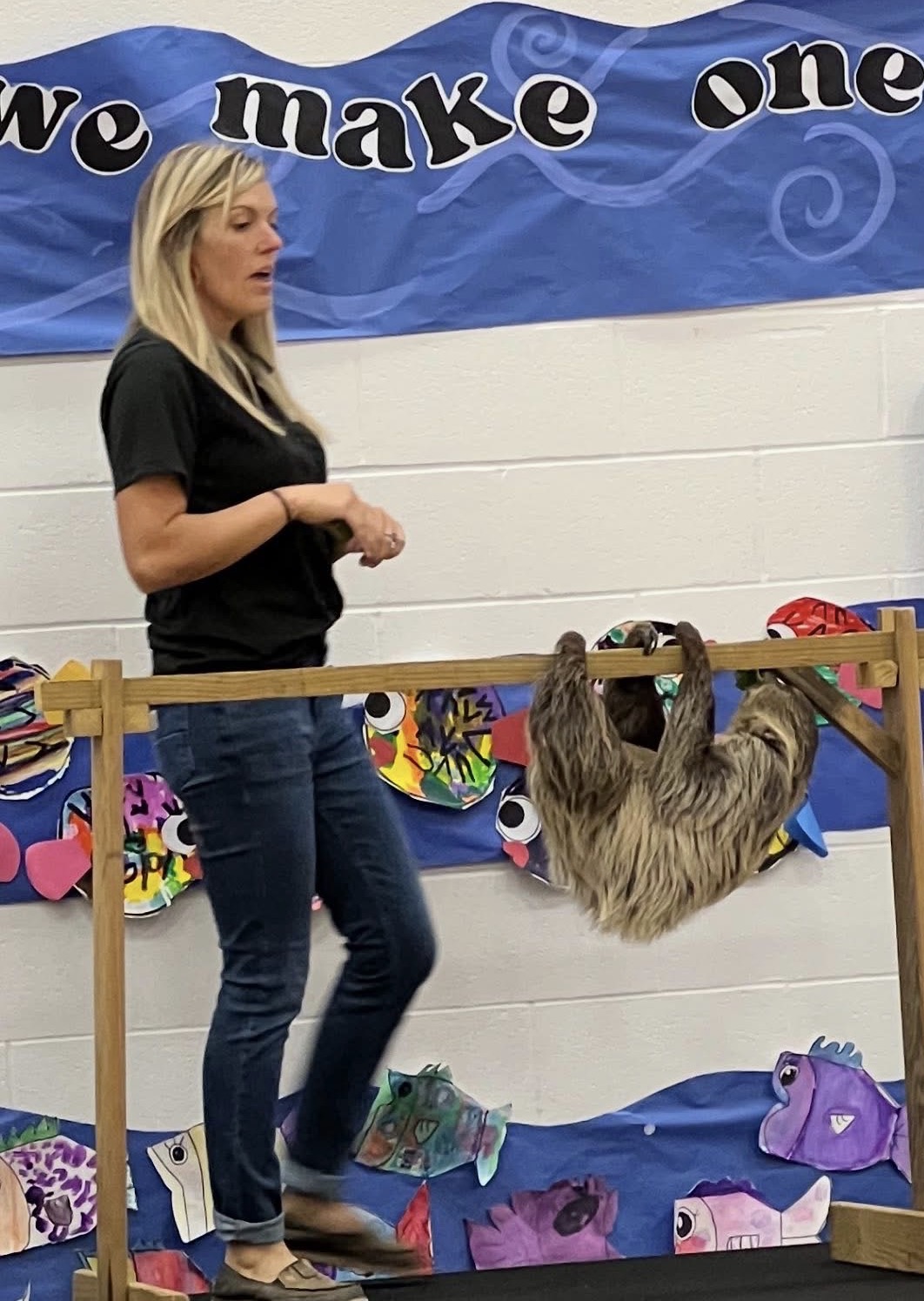 A Traveling Acres educator presenting a sloth during a school assembly